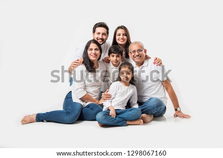 indian/asian family sitting over white background. senior and young couple with kids wearing white top and blue jeans. selective focus
