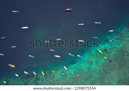 Beautiful marine landscape with many multicolored fishing boats near Gili Trawangan island in Indonesia. Sun is shining onto them. Top view horizontal aerial photo.