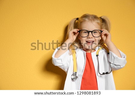 Cute child in doctor coat with stethoscope on color background. Space for text Royalty-Free Stock Photo #1298081893