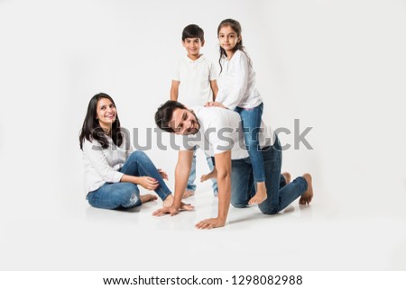 happy mad ride on father's back. Indian small girl sitting on Dad's back while mother and brother laughing. selective focus