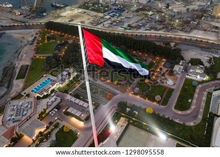 Unique aerial view of the United Arab Emirates flag waving at night. 