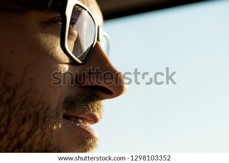 a face of a man with eye glasses looking out in the sun with a smile Royalty-Free Stock Photo #1298103352