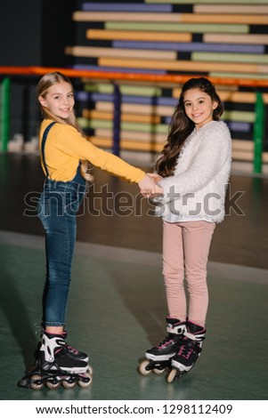 Selective focus of beautiful children on roller skates smiling and holding hands 