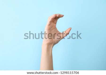 Woman showing C letter on color background, closeup. Sign language