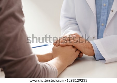 Male doctor comforting woman at table, closeup of hands. Help and support concept Royalty-Free Stock Photo #1298129233