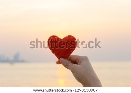 Valentines day concept, Love concept, Woman hand holding red heart  during sunset background.