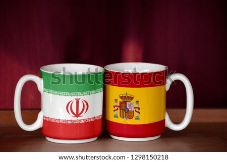 Spain and Iran flag on two cups with blurry background