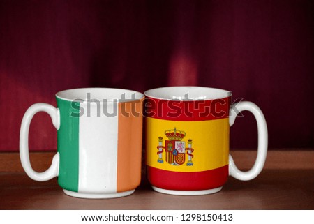 Spain and Ireland flag on two cups with blurry background