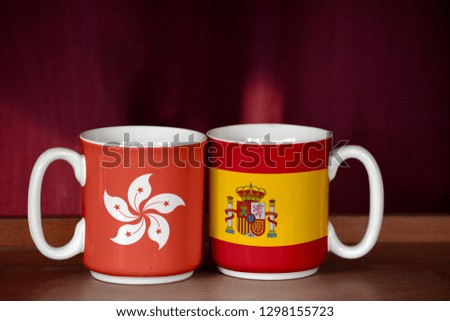Spain and Hong Kong flag on two cups with blurry background