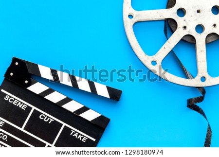 Filmings concept. Clapperboard and film stock on blue background top view copy space