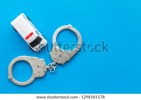 Police concept. Police car toy and handcuff on blue background top view copy space