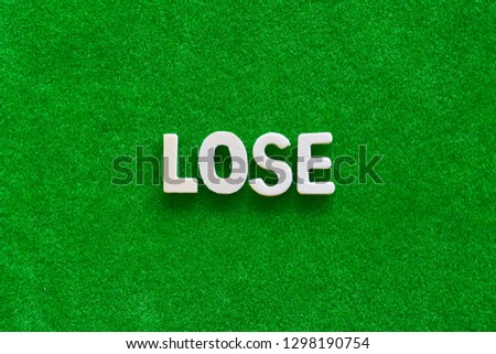 Wooden text on short grass field concept. The word "LOSE" on green background.