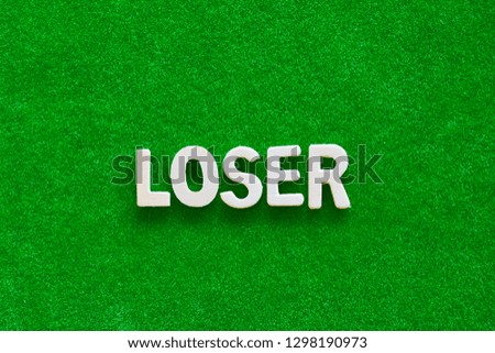 Wooden text on short grass field concept. The word "LOSER" on green background.
