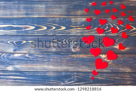 Small red paper hearts on the wooden background. Saint Valentine's day concept. Love and romantic photo. Postcard for holiday. Copy space place.