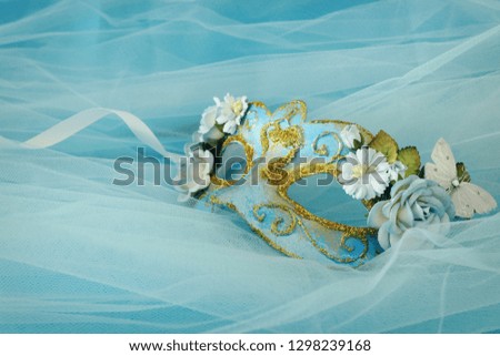 Photo of elegant and delicate gold and blue venetian mask over silk and chiffon background