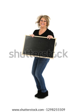 Portrait of a happy middle aged woman jumping while holding a blackboard against a white background