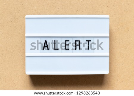 White lightbox with word alert on wood background