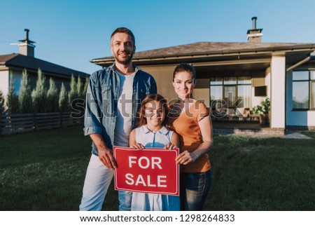 Cheerful nice family selling their house while standing on the yard