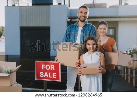 Waist up of a cheerful smiling family standing with boxes near their house