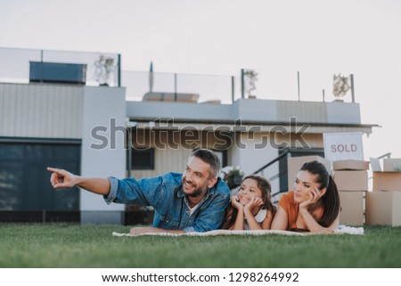 Nice smiling couple resting with their kid in the yard while resting together