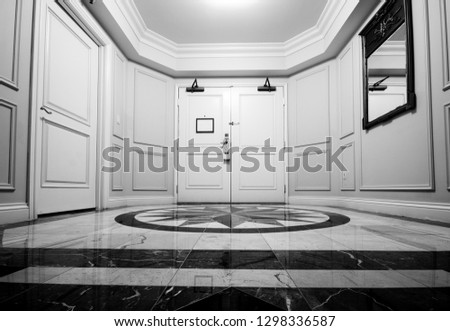 Anteroom with white double door and mosaic marble floor.
