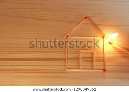 house laid with matches catching fire, arson, someone holding a burning match at the roof Royalty-Free Stock Photo #1298349352