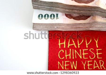 Stacks of Thai paper money bank note cash on the red envelope written HAPPY CHINESE NEW YEAR, a Chinese tradition money gift (Ang Pao) giving to family during holiday.