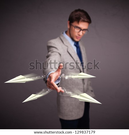 Handsome young man throwing origami airplanes