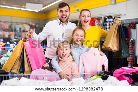 happy family of four with shopping bags in clothing shop