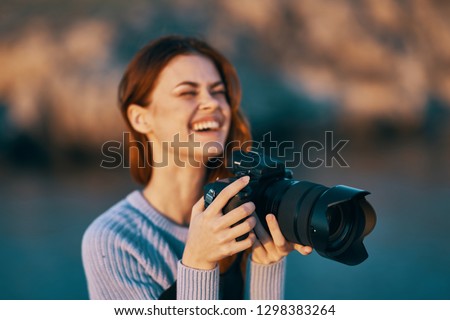 woman photographer with a camera in nature near the river laughs                