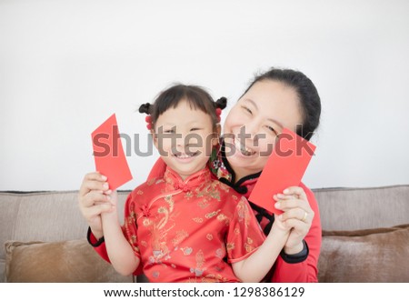 Asian family in red color Chinese traditional dress holding red packet money at home