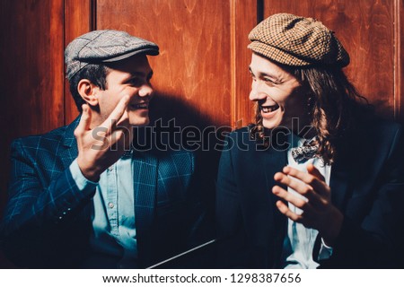 Retro portrait of two young people smoking hookah in a bar while talking. Concept of having a good time in retro style. smiling emotions