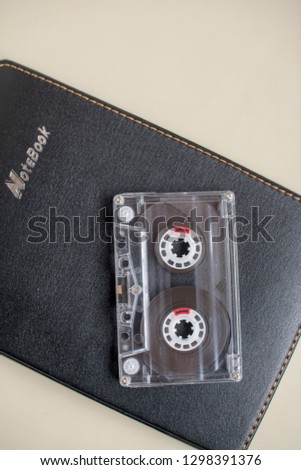 One plastic cassete for tape recorder and black notebook