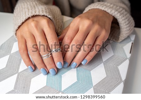 hands with blue color shellac manicure lie on the table with stripes background