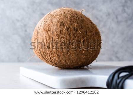 Fresh Organic Brown Raw Coconut on White Marble Board.