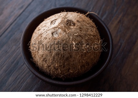 Fresh Organic Brown Raw Coconut in Dark Wooden Bowl.