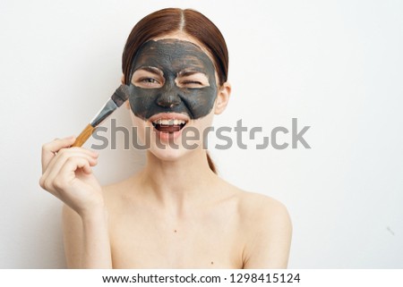 joyful woman applies a fresh skin on the face mask with a brush