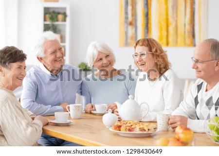 Group of happy older people laughing together on a coffee meeting at nursing home