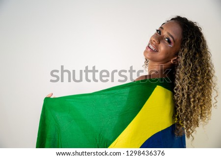 Happy black woman fan holding a Brazilian flag. Brazil colors in background, green, blue and yellow. Elections, soccer or politics.