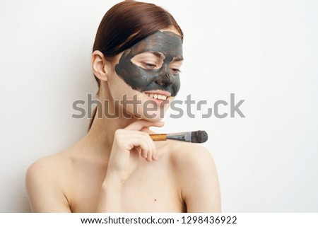 woman with a brush to put a clay mask on her face
