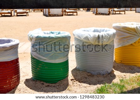 Four colors of rubbish cans on the beach, red, green, white and yellow garbage containers
