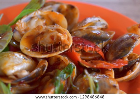 Stir fried clams with roasted chili paste in plate on wood table.Thai food.