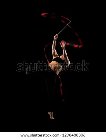 Woman doing rhythmic gymnastics with ribbon on black background