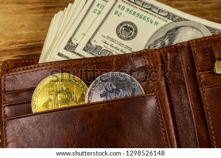 Wallet with american hundred dollars bills and bitcoins on wooden background
