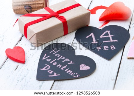 Gifts and decorative hearts with inscription on a wooden background