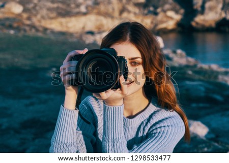 Counter photographer with a camera near the face takes pictures of nature in a blue sweater Tourism