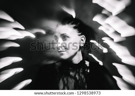 Abstract black and white photo: a young woman is dancing in a hypnotic disco, light is reflected on the background on a long exposure