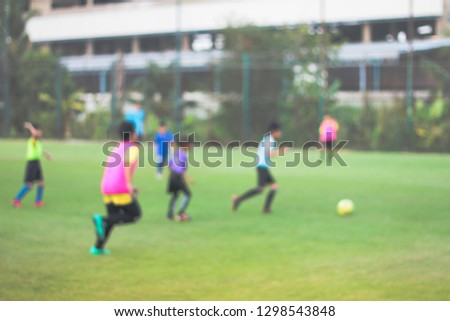 blurred picture of young boys playing football match on green grass