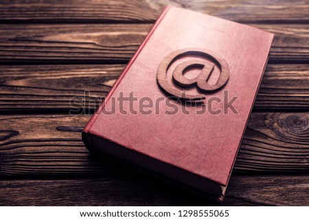 email sign on book on wooden table background. Internet, electronic communication.