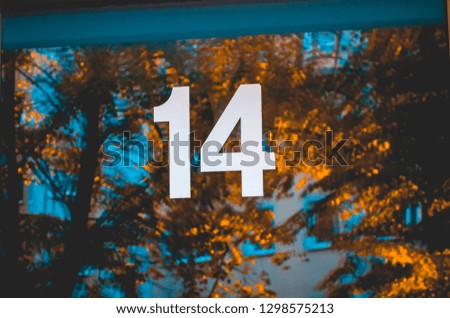 door with white number 14 and orange trees in the reflecting glass